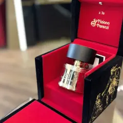 Złota butelka perfum Kirke Tiziana Terenzi w aksamitnym, czerwono-czarnym pudełku z greckimi zdobieniami.