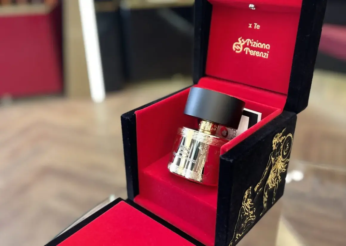 Złota butelka perfum Kirke Tiziana Terenzi w aksamitnym, czerwono-czarnym pudełku z greckimi zdobieniami.